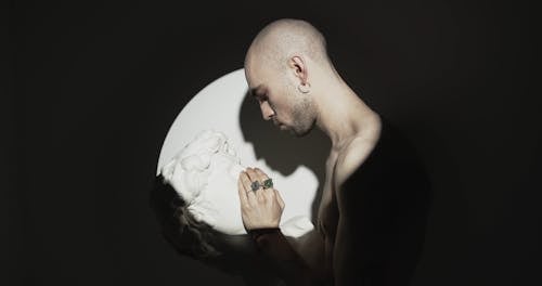 A Man Touching The Face Of A Head Bust Sculpture