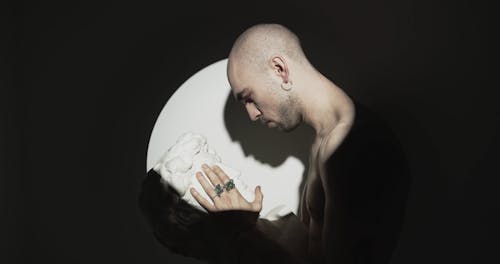 A Man Lovingly Touching The Face Of A Head Bust Sculpture