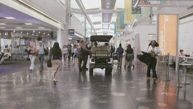 busy airport terminal with travelers and electric cart