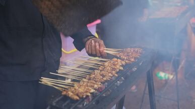 grilling chicken satay on street market