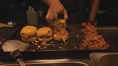 street food vendor preparing juicy burgers