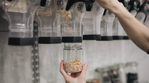 Person Transferring Mixed Beans on a Glass Container