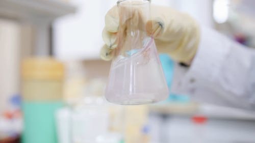 A Scientist Mixing Liquid On a Glass Flask Inside A Laboratory