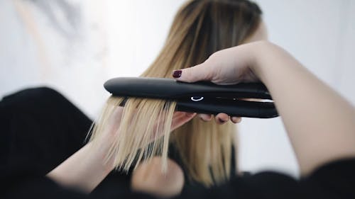 A Woman Receiving Hair Straightening From A Hair Dresser