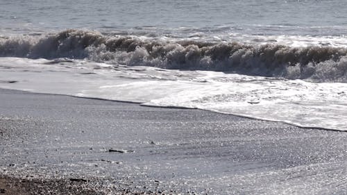 Морские волны, целуя гладкий песок на берегу моря