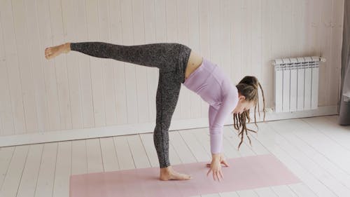 Une Femme Faisant Des Exercices D'étirement Et D'équilibrage Sur Un Tapis