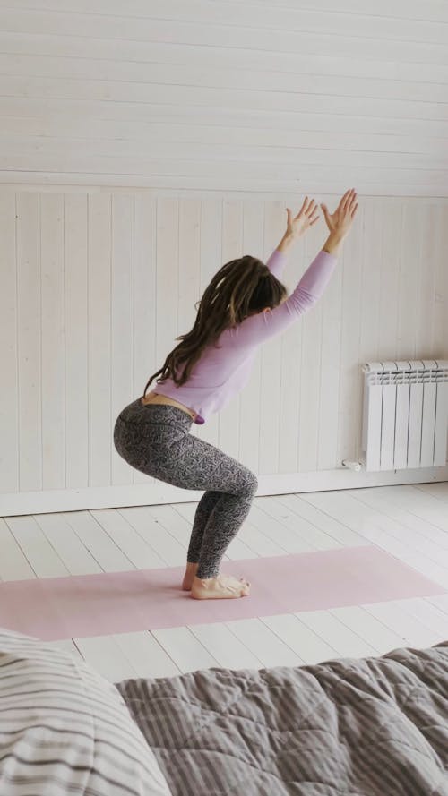 A Woman Doing Exercise Movements Over A Mat On The Bedroom Floor