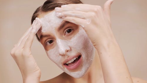 A Woman Applying Face Mask on Her Face