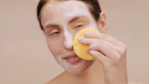 Woman Cleansing Her Face With Soap And Sponge