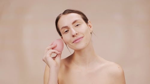 Woman Using Pink Sponge on Her Face