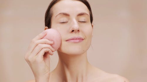 Woman Using Pink Sponge on Her Face