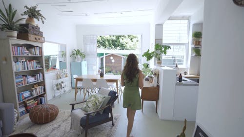 Woman In Green Romper Pouring Water On The Plant