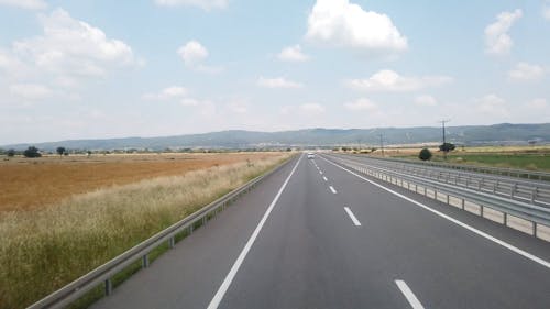 Traveling On A Highway Built Across A Vast Land Of Grass Field