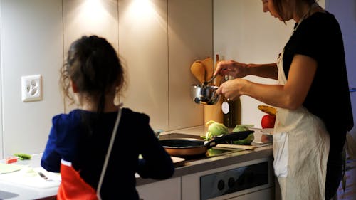 Eine Mutter, Die Unterstützung Von Ihrer Jungen Tochter Bei Der Zubereitung Einer Mahlzeit Erhält