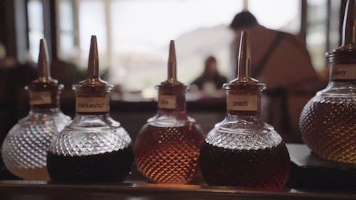 Bottles Of Different Flavors Lined Up In A Bar