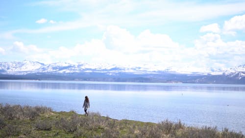 A Woman Walking By The Lakeside Enjoying Nature's Beauty
