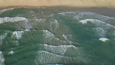 aerial view of ocean waves and sandy shore