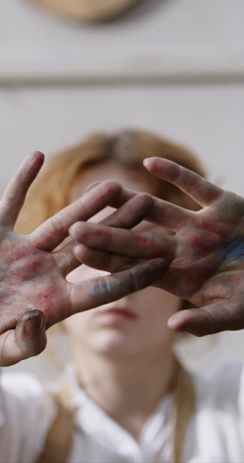 一个女人展示她充满了油漆的手