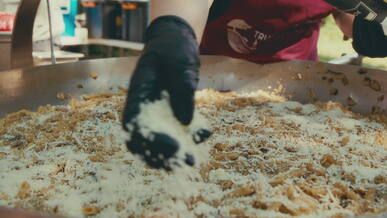 chef sprinkling cheese on giant outdoor pasta dish