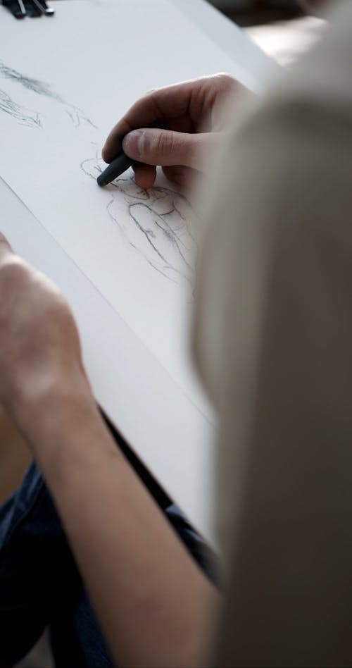 An Artist Sketching A Person Using Charcoal Pencil