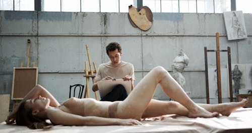 An Artist Sketching A Woman Who's Lying Down On Her back