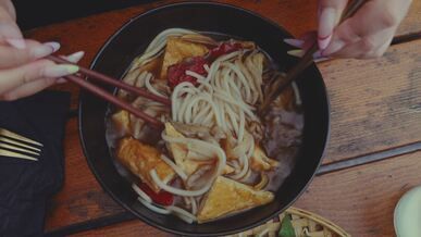 close up of udon noodles being mixed and served