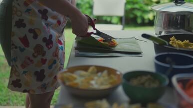 woman prepares food with fresh ingredients outdoors