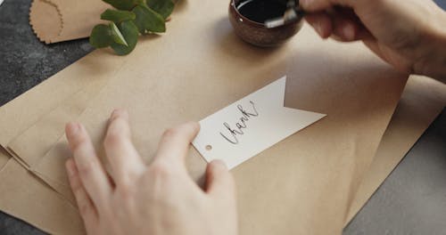 Writing "Thanks" In Caligraphy On A Paper Tag