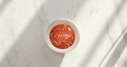 Back Playing A Video Of Pouring Alphabet Letters Pasta Noodle On A Bowl Of Tomato Puree
