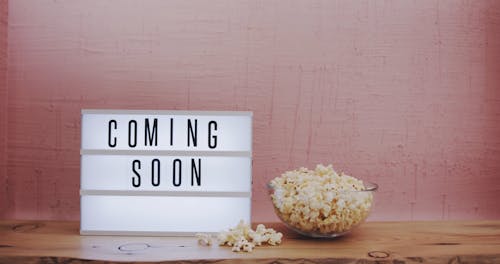 Bowl Of Popcorn Besides A Light Text Box With A Coming Soon Sign