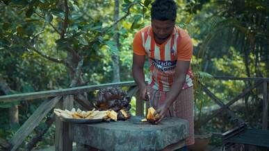 man preparing tropical fruit in scenic forest