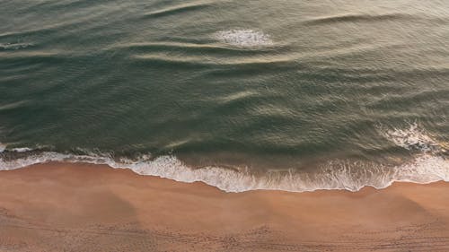 Drone Footage Of A Beach With Small Waves Hitting Its Shore