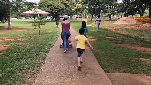 A Mother and Her Kids Strolling at the Park