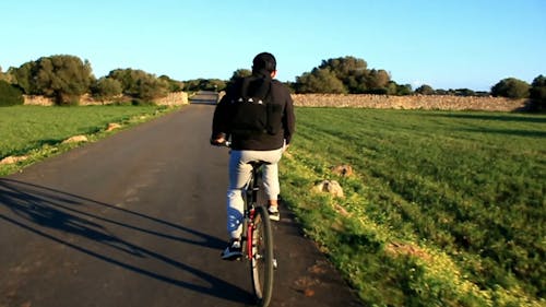 Man Riding Bicycle On Asphalt Road