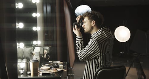 A Male Photographer Testing Her Camera Looking Through A The Dresser Mirror