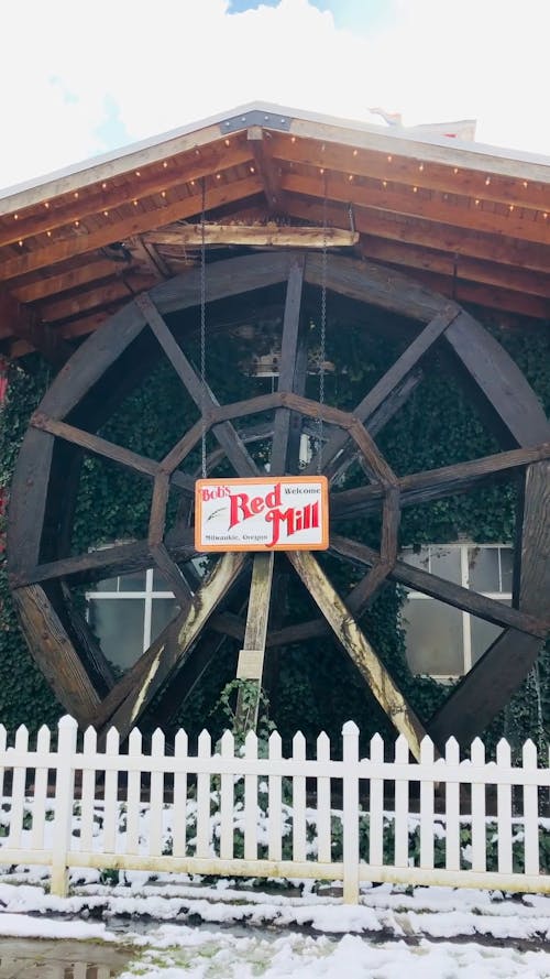 A Waterwheel Outside The Store With Red Mill Signage