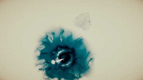 Droplets Of Blue Ink Over A White Liquid