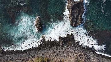 drone footage of waves crashing on a rocky shore