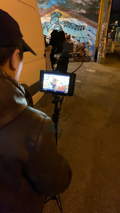 A Man Filming A Group Using a Video Camera