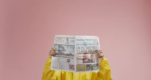 A Man In Protective Suit Is Reading A Newspaper