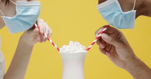 A Couple Wearing Masks, Sharing A Glass Of Milkshake 