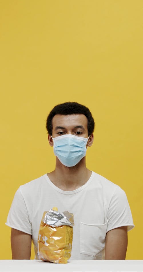 A Man Eating A Sack Behind His Surgical Mask