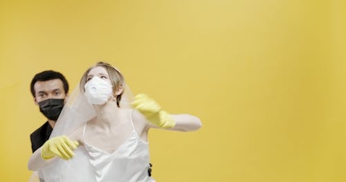 A Couple Dancing In Their Wedding Dress While Wearing Protective Masks