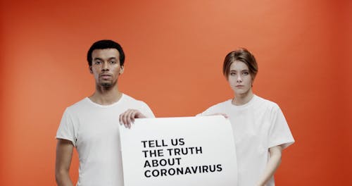 Two People Holding A Slogan Asking About The Truth In Coronavirus