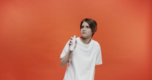 A Woman Warily Spraying Disinfectant In The Air