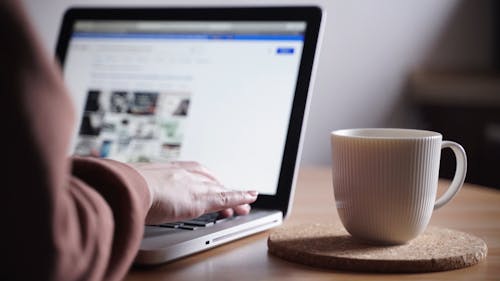 A Person Working On A Laptop At Home