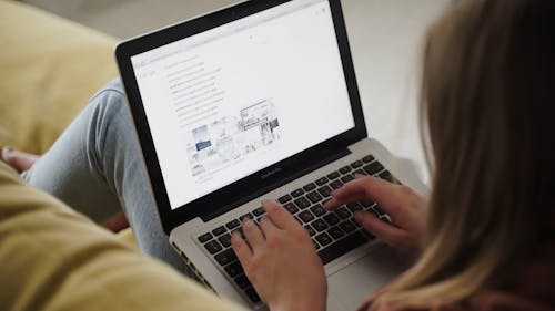 Person Sitting on Sofa Using a Laptop