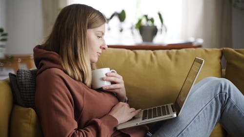 Woman Sitting on Couch Using a Laptop