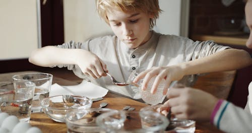 A Boy Mixing A Spoonful Of Vinegar To Make A Solution