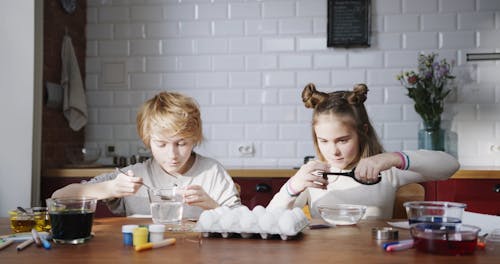 A Girl And A Boy Making Their Bowls Of Liquid Coloring To Make Easter Eggs